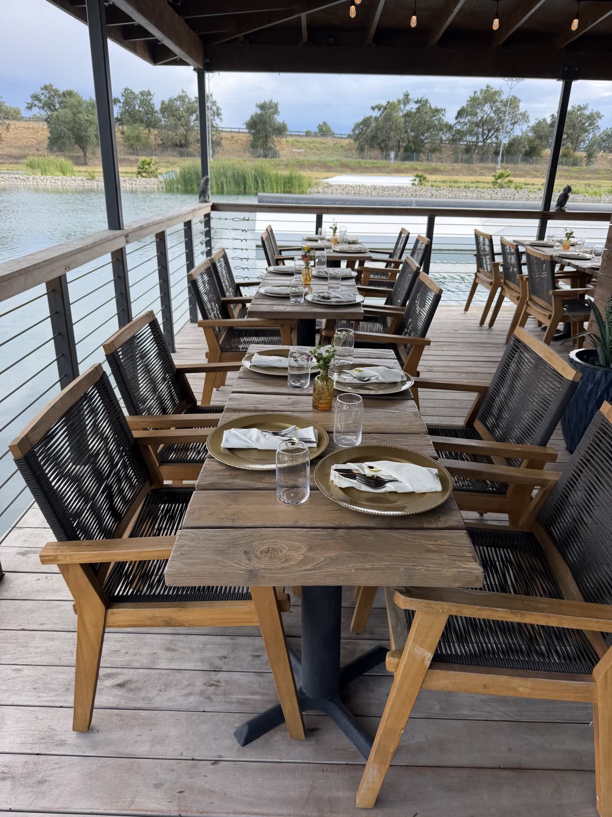 Deck tables set with gold chargers over the water