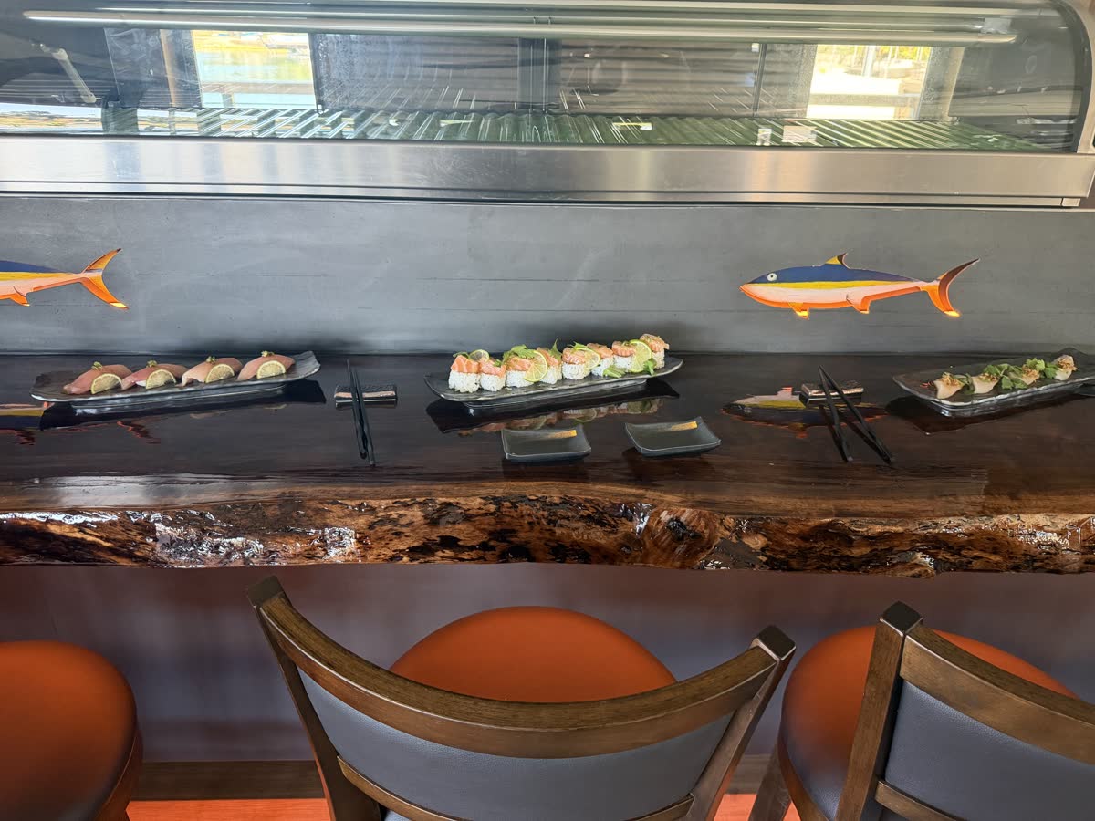 The live-edge walnut sushi counter with plated rolls and painted tuna wall art
